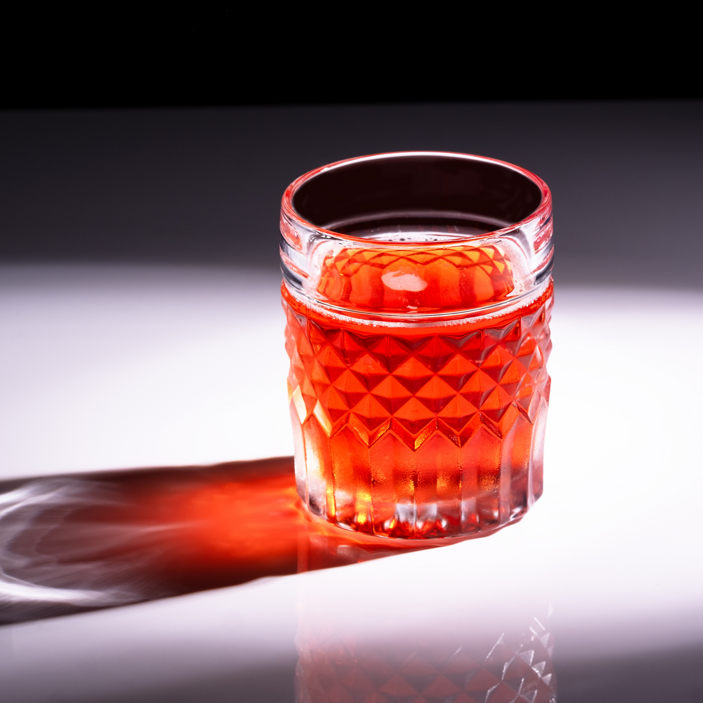 Prestige whiskey glass privilege collection — high-end gift set for dad who drinks scotch Red glass tumbler with textured design on a reflective surface