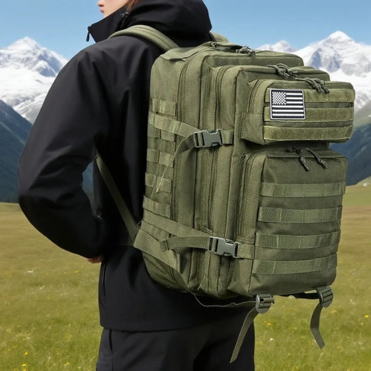 Tactical backpack in olive green worn on the back while hiking with mountains in the background