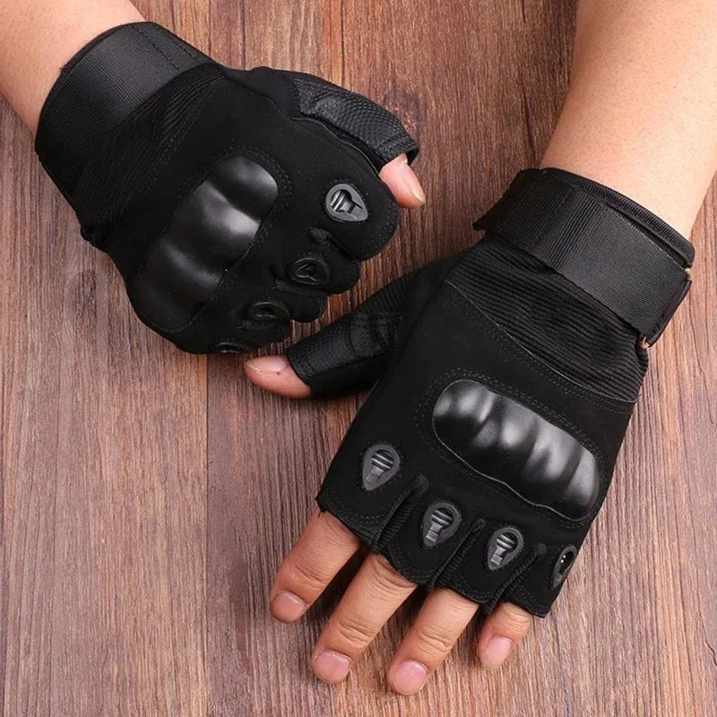Tactical half-finger gloves in black with hard-shell knuckle guards on a wooden surface