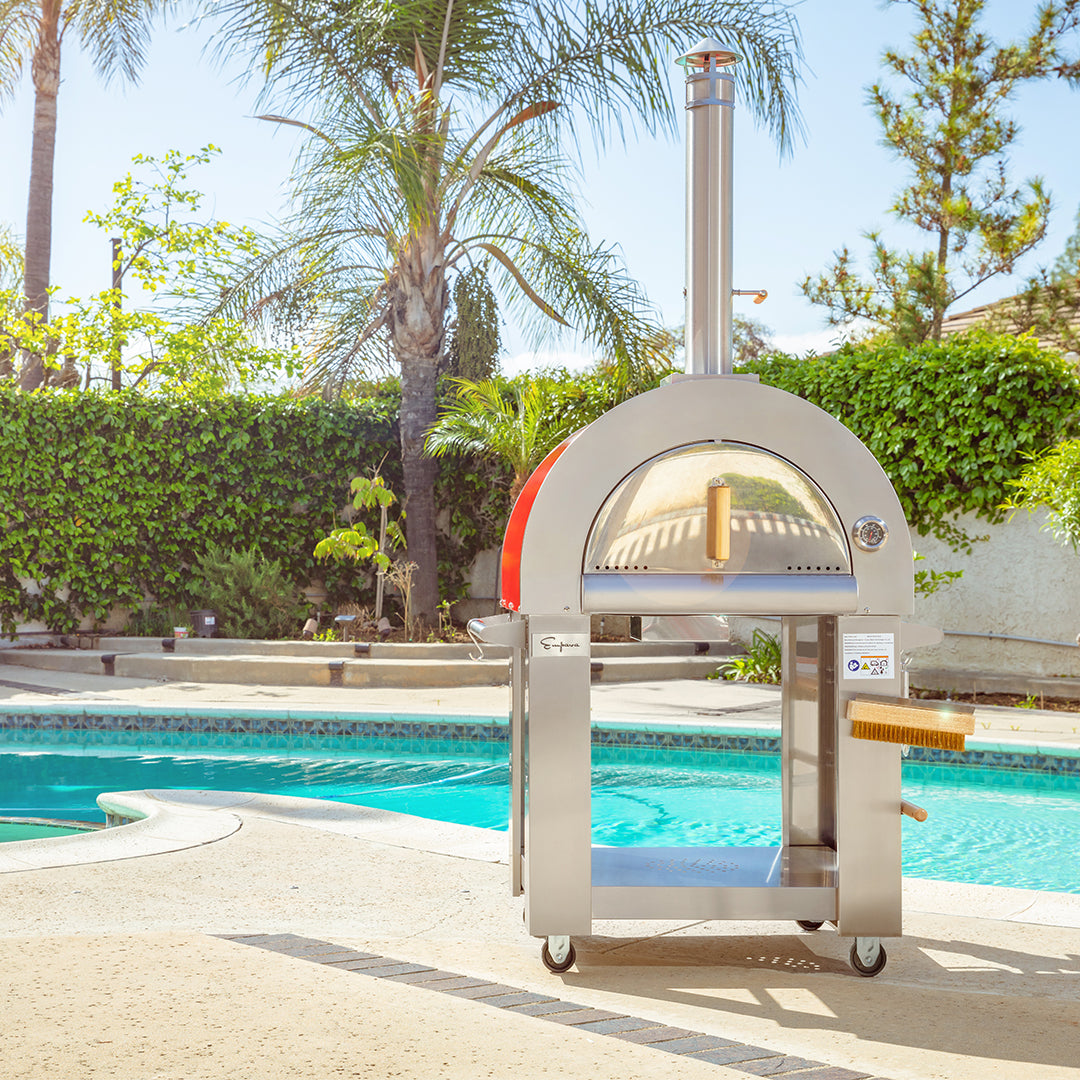 Outdoor pizza oven by a pool with palm trees and greenery in the background Empava outdoor wood-fired pizza oven — unique BBQ and cooking gift for dad